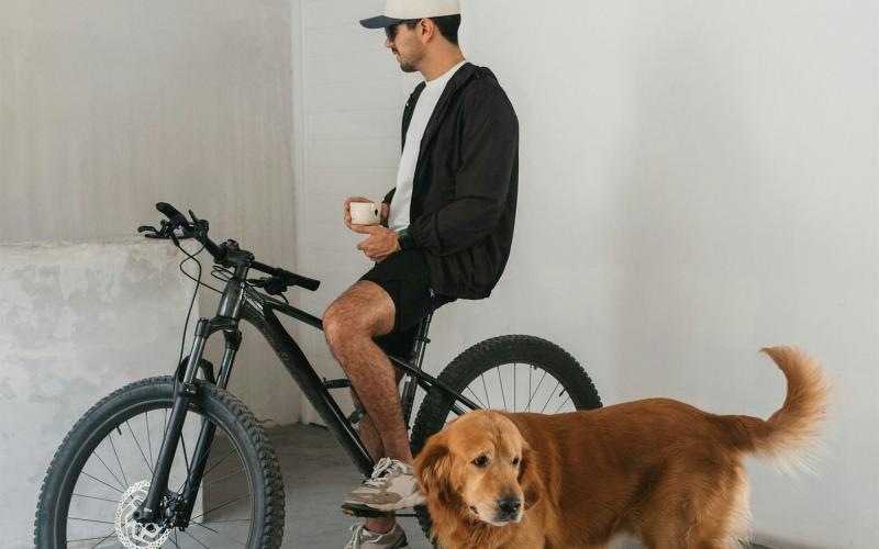 a man sitting on a bike next to a dog